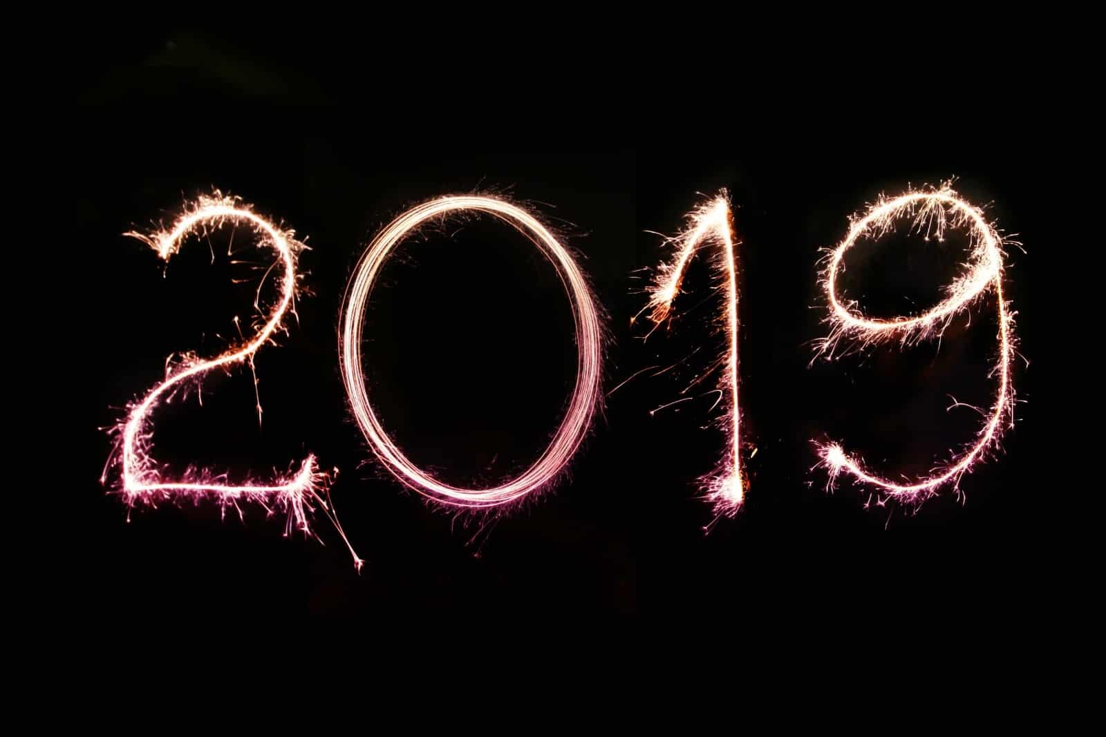 The image displays the year "2019" written with bright sparklers against a completely black background, creating an energetic and celebratory effect.