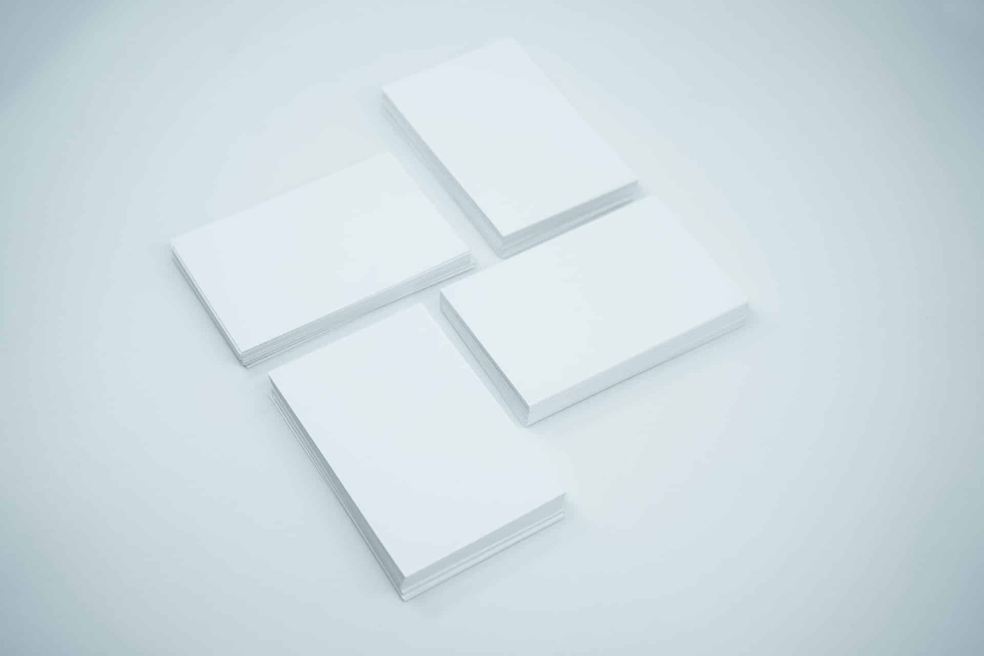 Four stacks of blank white paper are arranged on a light grey surface. The evenly spaced stacks seem ready for the next phase of Pre Approval Reports, each stack consisting of several sheets.