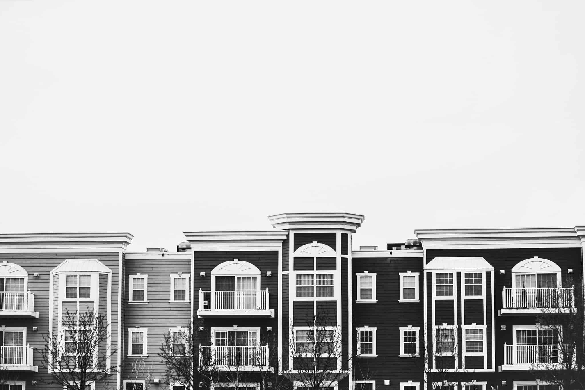 Black and white photo of multi-story apartment buildings with fire escapes in an urban area