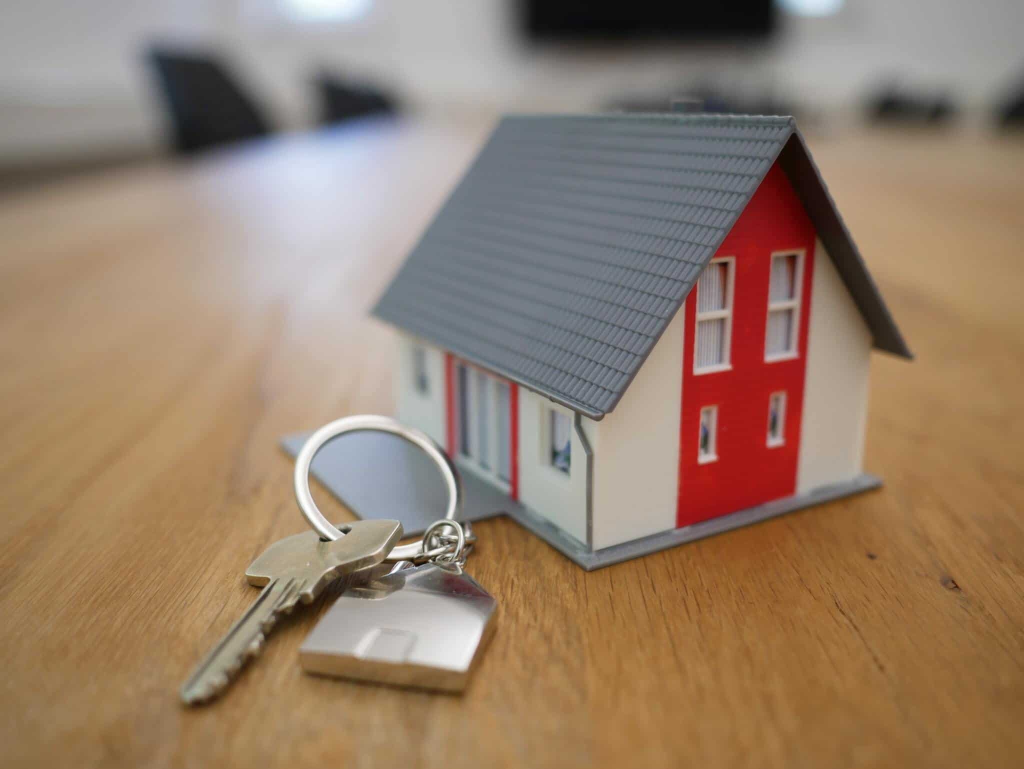 Miniature house and keys on a wooden surface representing real estate or property ownership and investment concepts